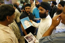 Members of Wisconsin's Sikh community look at a mug shot of Wade Michael Page / Photo by Getty Images
