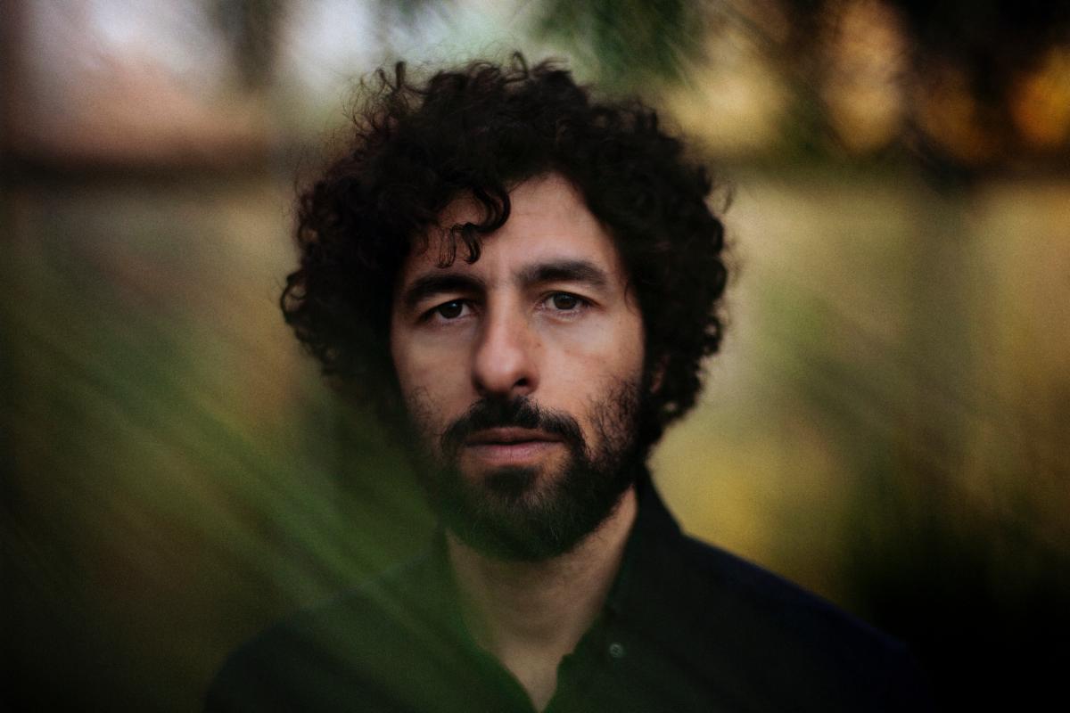 On the Record: José González’s <i>
<p> </p>
<p><strong>Was your process for <em>Local Valley</em> different from your other albums?</strong><br />
Yes, it was different. I can mention the ways it was similar. I’m on my own, I do my guitars, and then the melodies, and then the lyrics, and then I record it on my own and then I take some help to mix it and master it, but it’s very solitary stuff. It’s similar also because I’ve been sticking mostly to just guitar and vocals, but this time, as soon as I had maybe half the album with guitar and vocals, I wanted to put my producer hat on and mix it up a bit and change styles. That’s when I started using the drum machines and loop the vocals and guitars and also switching between styles of production.</p>
<p>I have one song in Swedish, which I made in a very sacral style, like if I was in a church, compared to the “Head On”, which is more oriented in Western African style. Also, I guess another difference is how I wrote and recorded, which is in the countryside instead of in the city, in a dark room. I was more in a wooden room with the windows to nature.</p>
<p><strong>How did being immersed in nature influence the process?</strong><br />
It just flows—it’s been flowing better than my writing and my recording. Maybe it’s because of the breaks, but maybe also because of nature. Being in a lighter mood and not getting stuck as often, I think it gives the album a more open feel. Of course, all the nature-inspired metaphors that I’ve been using in the last two albums, I think that’s probably because I think about lyrics while I’m running or walking in nature.</p>
<p><strong>How was it creating an album in three languages?</strong><br />
This time it was actually easy. I didn’t feel like it was hard at all, but the times that I tried before, I felt like I got stuck and switched to English, and then all of a sudden, it flowed. It’s been fun this time in terms of not getting stuck with music or not getting stuck with lyrics. In a way, just wanting to try different styles and try different languages. In many ways, I feel like I’m presenting more of myself. The Caribbean style in “Swing” is more in line with what I like to listen to at home. I don’t like to listen that much to whiny singer-songwriters.</p>
<p>Then the lyrics are, of course, my two mother tongues and then English, which is the language that I speak so much. When I tour and when I read, it’s mostly English, so I’m presenting more of me and then it felt natural to include all three languages.</p>
<p><strong>How has this specific time in your life influenced the writing?</strong><br />
Just switching from being in a relationship to building a family and raising two children, that of course has made me look differently at who I am, or want to be. Talking to my four-year-old daughter in Spanish when she was a toddler, I think that helped also in terms of easing up my language.</p>
<p><strong>What’s the story behind the album title?</strong><br />
<em>Local Valley</em>, I’m referring both to the song “Valle Local”, where I’m thinking about tribes being stuck in a local valley where they can’t communicate and they can’t find this nicer valley that’s nearby. I’m thinking about culture clashes, about the alternative facts or just the ideologies that seem to clash, people can’t get past getting stuck into tribal mentalities. That’s one way of thinking about the title.</p>
<p>Another one is more connected to the songs “Visions” and “El Invento”, where I’m thinking about humanity, again, being stuck in this local valley, but this time Earth and how this is our Goldilocks place, both in time and in a universe where we have been thriving for a while and how we want to continue thriving. That’s <em>Local Valley</em>, the place where we are as a humanity.</p>
<p><strong>Any special collaborators that made <em>Local Valley</em> happen?</strong><br />
Yes, of course. My girlfriend made the album cover. She’s been doing textile design. We’re both into Josef Frank, a Swedish textile designer. Basically, we just made a mood board with his stuff and we both felt like we should use inspiration from the drawings where there’s this black background and then lots of leaves and animals in bright colors. I think she did an amazing job with that.</p>
<p> </p>
<img decoding=