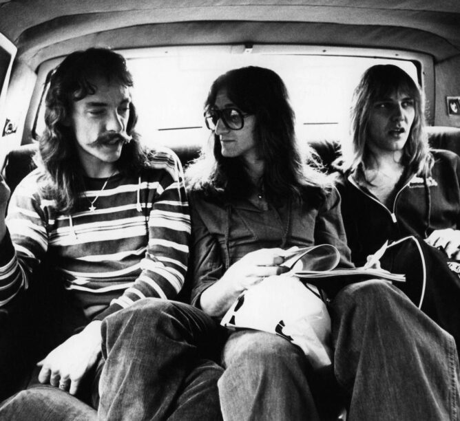 Neil Peart, Geddy Lee, and Alex Lifeson during the All The World's A Stage tour, 1977. (Credit: Fin Costello/Redferns)