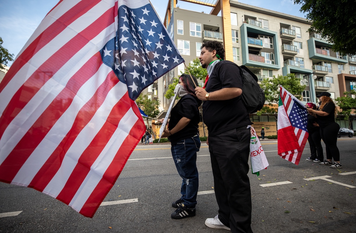 Two protesters carrying U.S. flags  during the "No Kings" protest against Donald Trump in downtown Los Angeles.