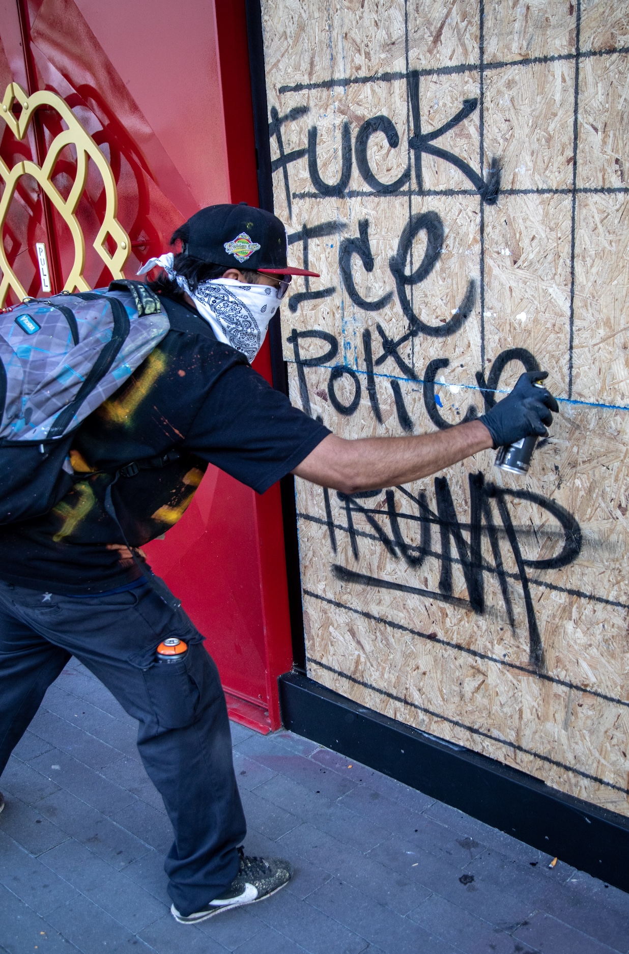 A graffiti artist leaves an anti-ICE/Trump message on a wall during the "No Kings" protest against Donald Trump in downtown Los Angeles.