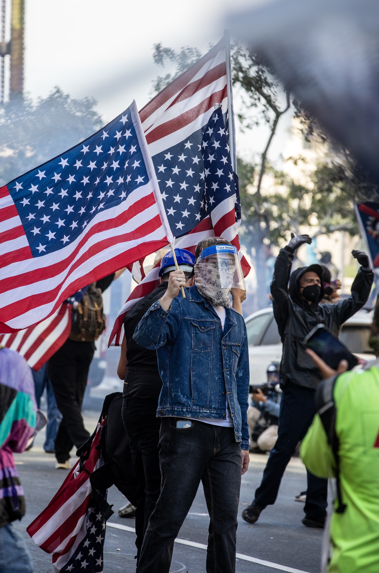 A protester carries U.S. flags and wears a gask mask outside of L.A. City Hall during the "No Kings" protest against Donald Trump in downtown Los Angeles.