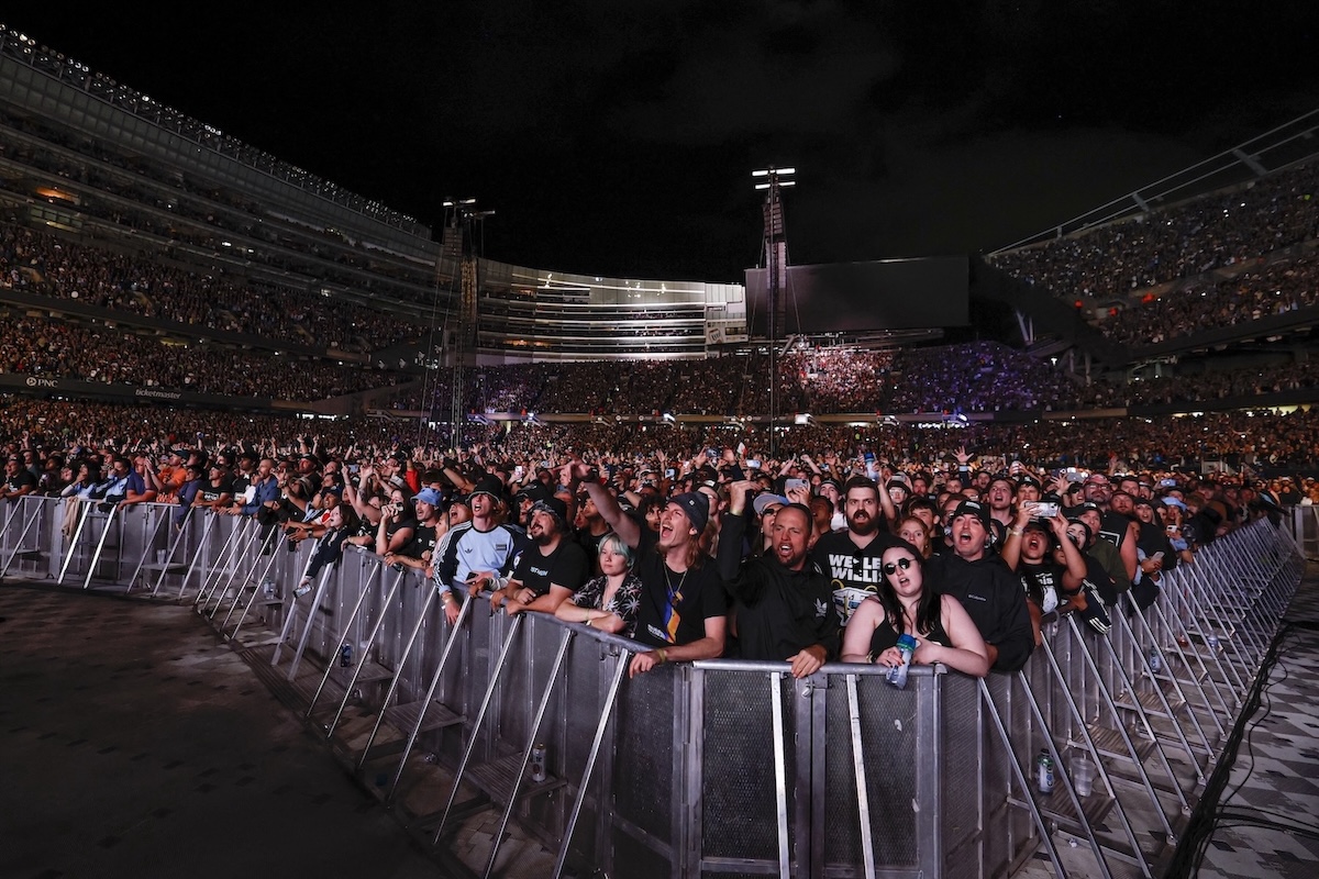 Fans watch Oasis perform on stage at Soldier Field in Chicago on August 28, 2025, during their reunion tour. (Credit: KAMIL KRZACZYNSKI / AFP)